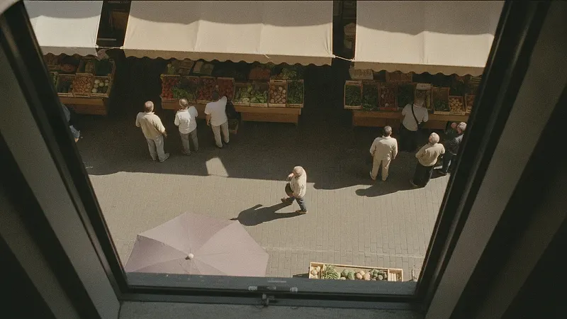A weekend market street from above, adults in twos and threes and one person walking through the middle.